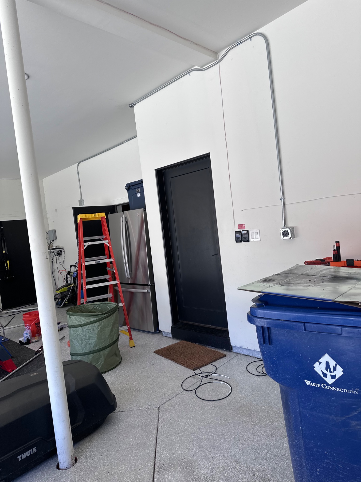 Metal conduit routed above a garage doorway to a wall-mounted receptacle